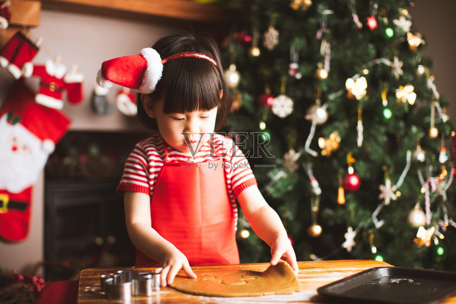 小女孩在圣诞树前做姜饼人照片摄影图片
