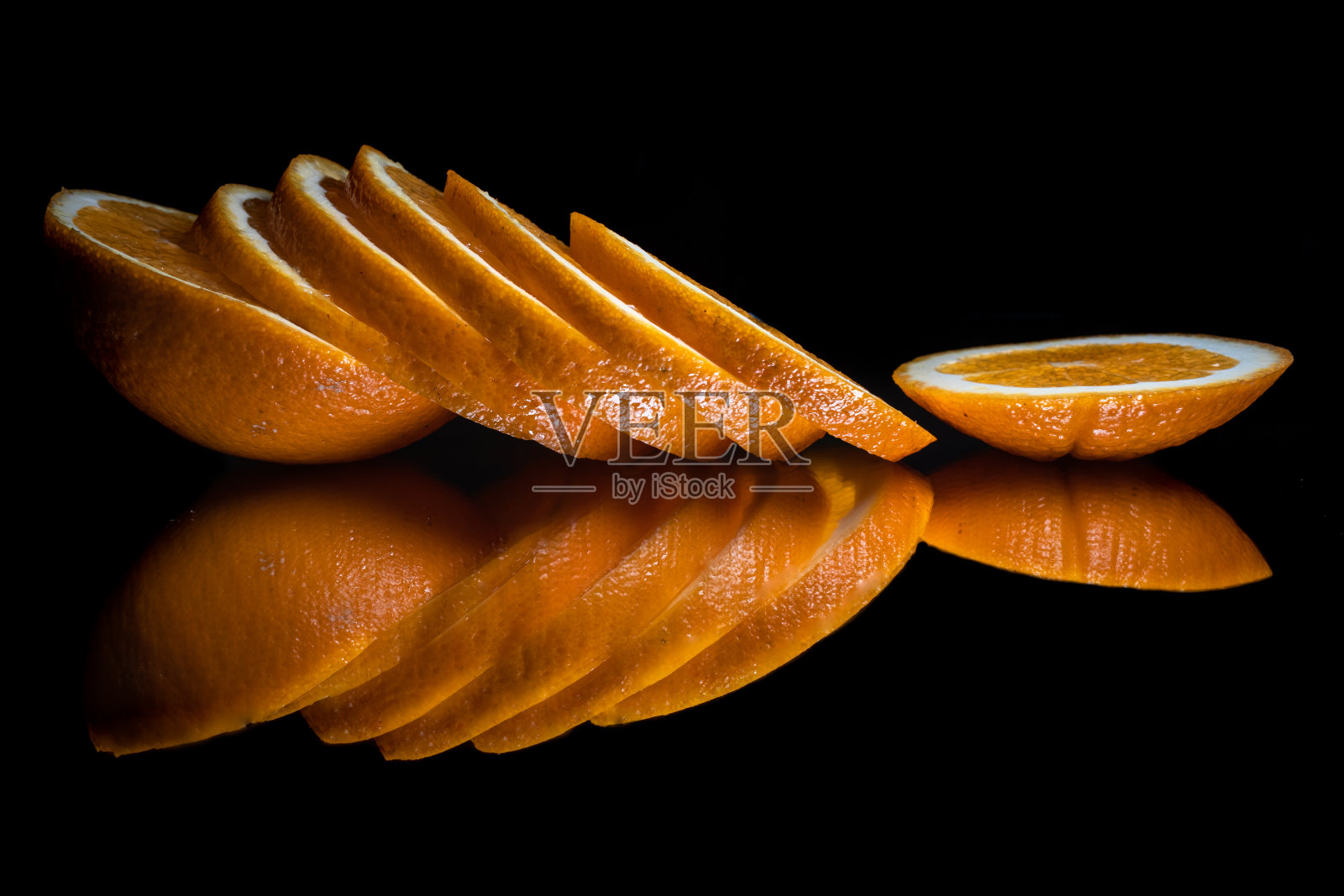 新鲜的有机橙色水果，切片，反光在黑色的背景上照片摄影图片