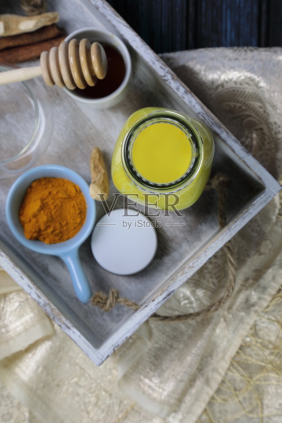 姜黄拿铁、黄金牛奶或含有超级食物姜黄粉、姜粉和肉桂的印度抗炎Doodh，在木质背景下用蜂蜜加糖照片摄影图片