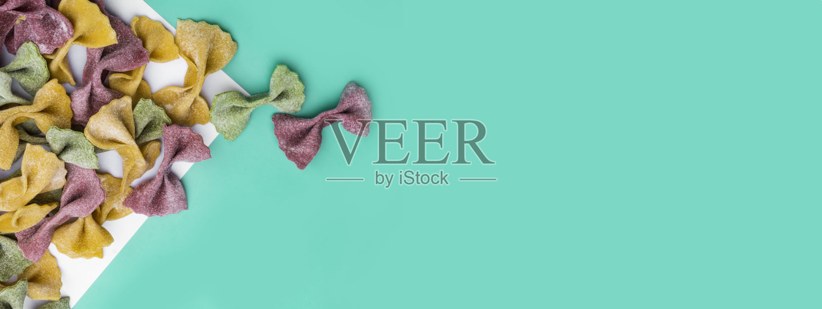 一堆意大利干三色法法尔意大利面。各种颜色的领结，绿色薄荷色背景，时尚照片摄影图片