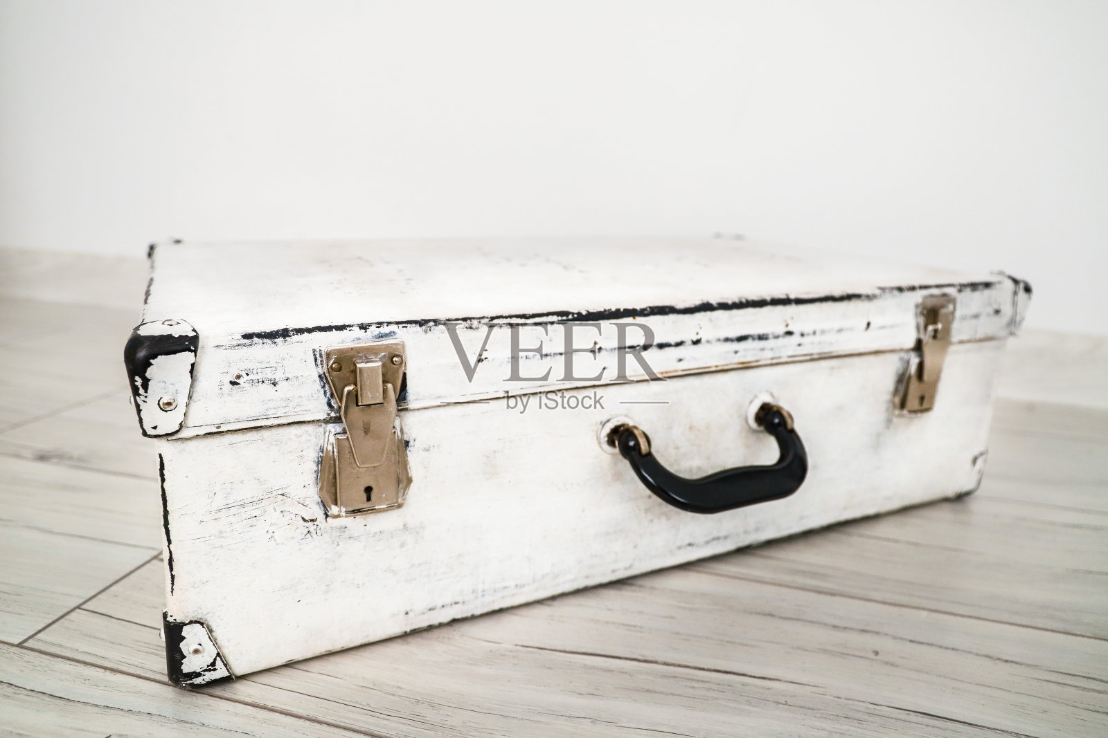 地板上放着旧的白色行李箱。照片摄影图片