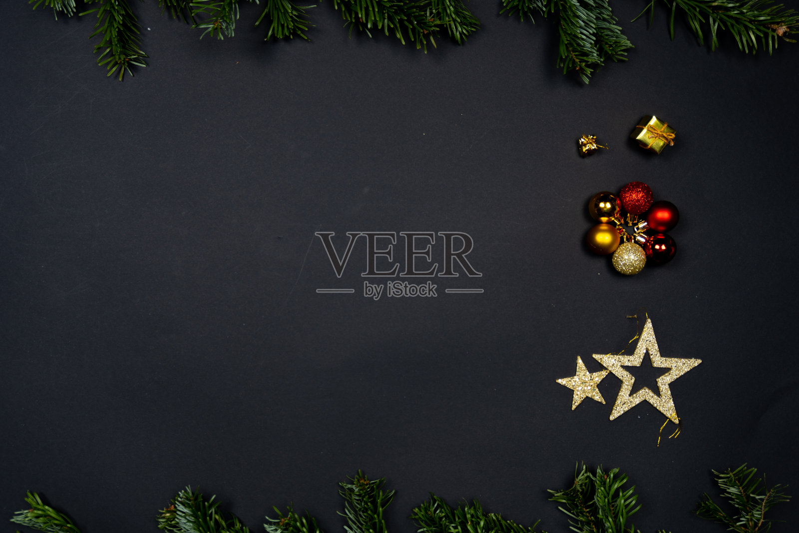 圣诞装饰品(圣诞装饰物，星星和小礼物)在黑色的背景框架下的冷杉树枝照片摄影图片