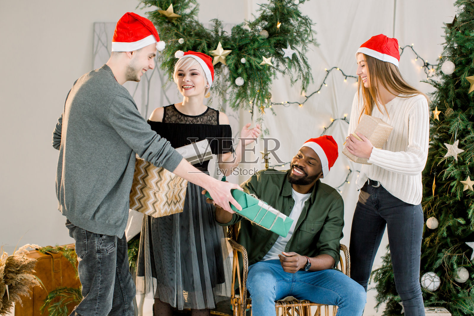 图为一群朋友在家里庆祝圣诞节并交换圣诞礼物照片摄影图片