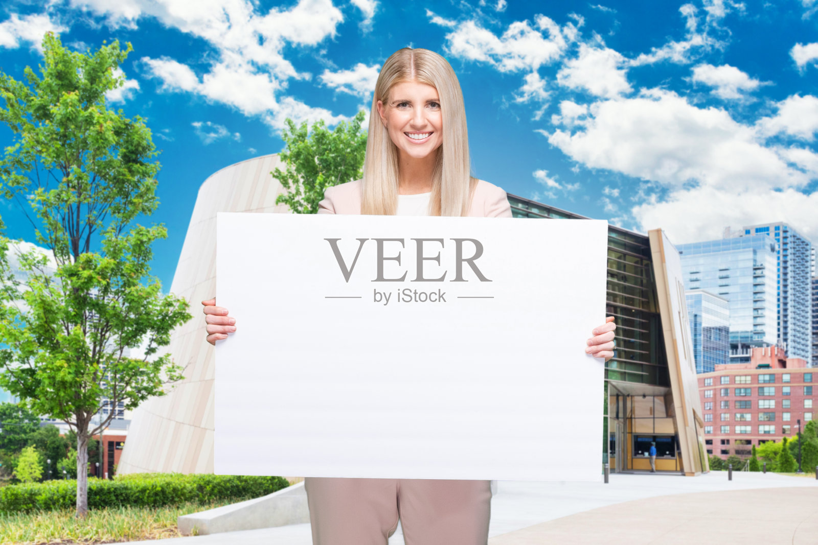 一个人/腰部以上/正面视图/看着相机的成年美丽的金发白人女性/年轻女性商人/商人站着穿着商务装/套装谁是微笑/快乐/愉快/大笑/凉爽的态度照片摄影图片