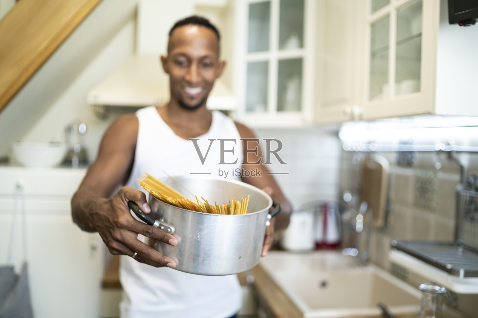 笑容满面的非洲裔男子在家准备意大利面照片摄影图片