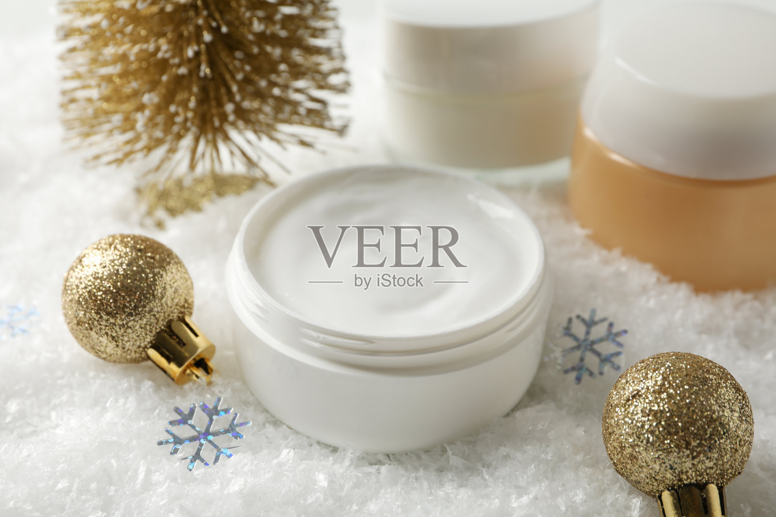 一罐冬季护肤霜，圣诞树和玩具上的雪背景，文字空间。特写镜头照片摄影图片