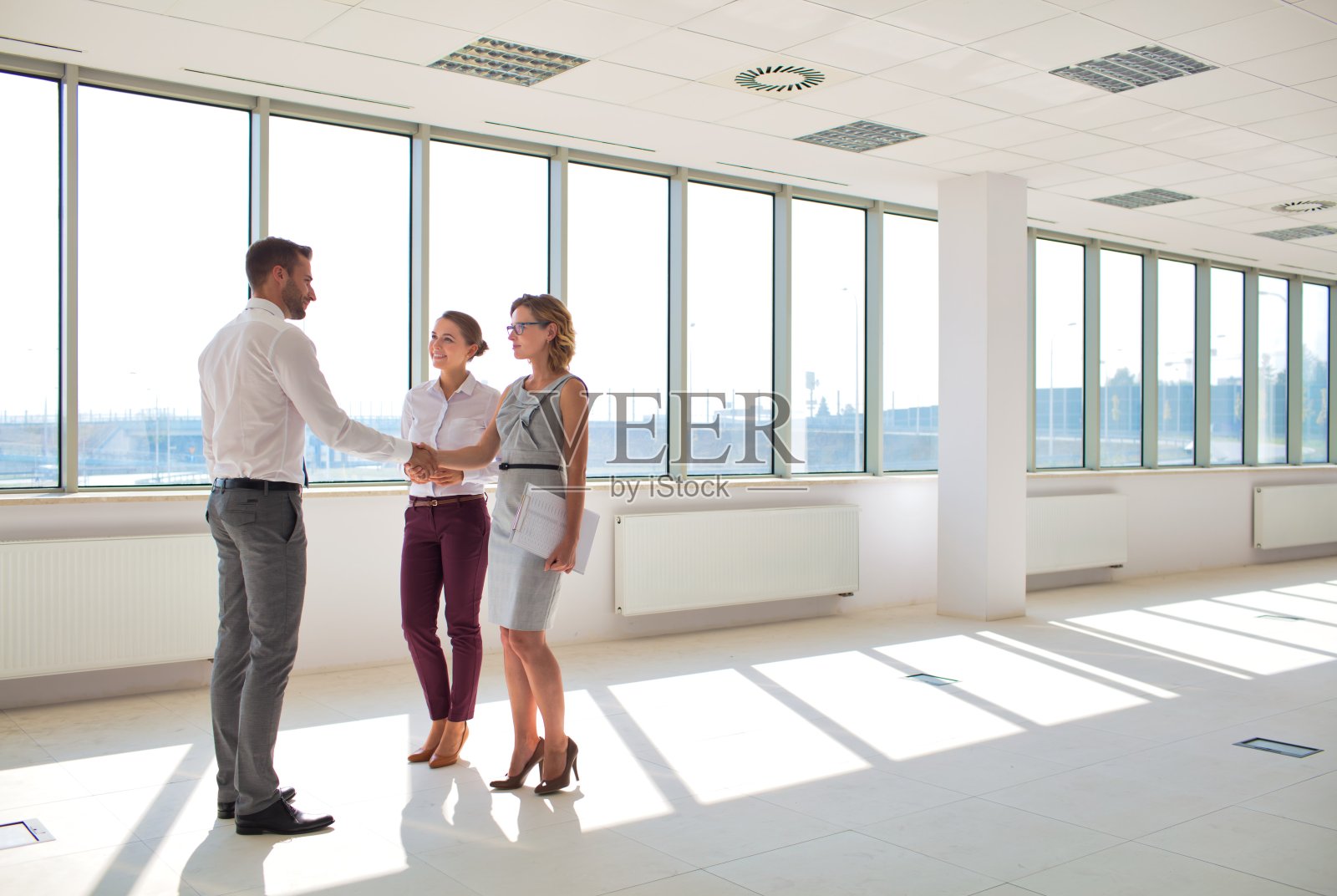 新办公室里，年轻商人与女商人握手问候照片摄影图片