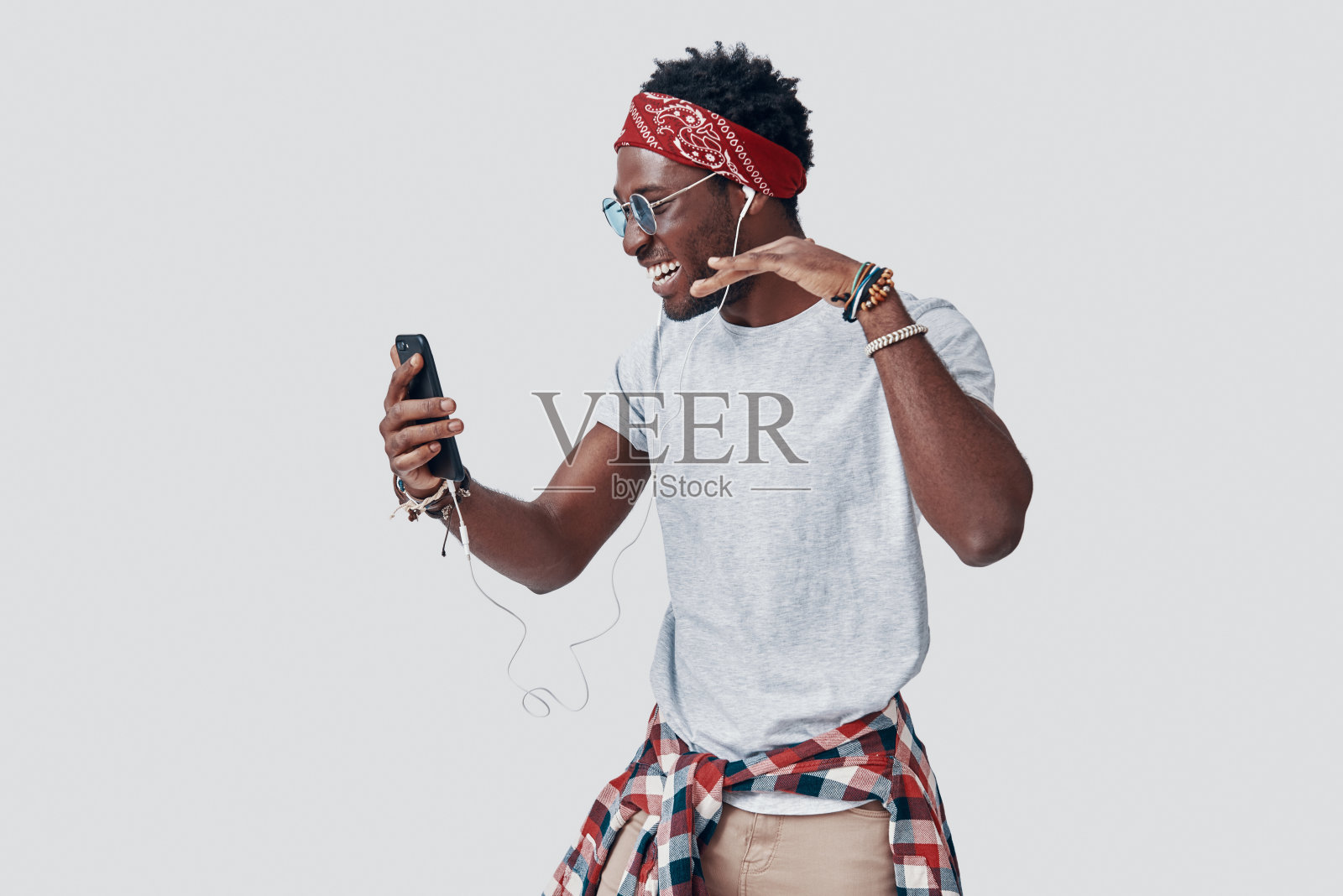 听着音乐，在灰色背景前微笑的年轻非洲男人照片摄影图片