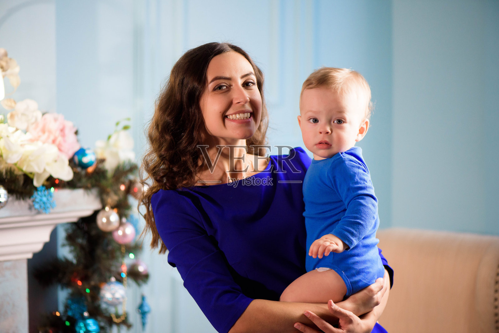 幼童和妈妈在节日装饰的房间里的圣诞树。照片摄影图片