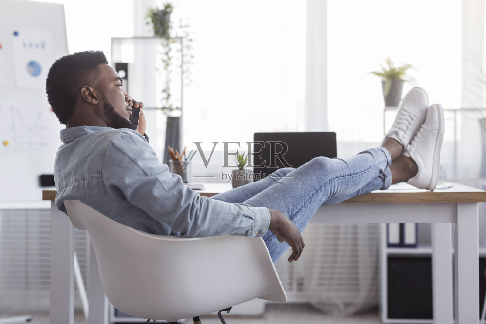 非洲裔员工在办公桌上玩手机照片摄影图片