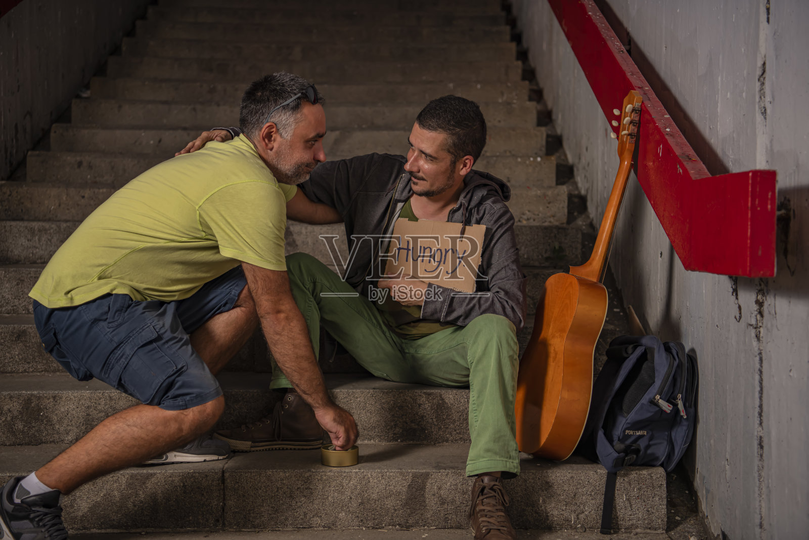 带着吉他的无家可归青年正在接受捐款照片摄影图片