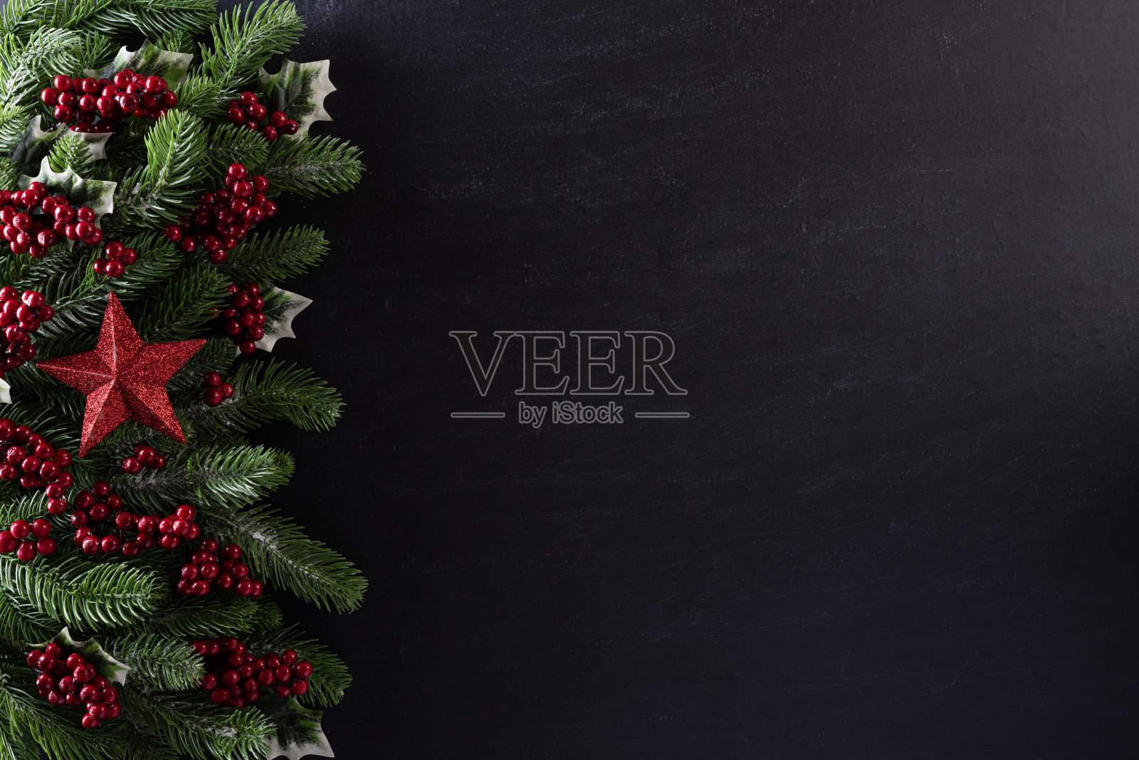 圣诞背景的概念。顶视图的圣诞礼物盒红球云杉枝，松果，红色浆果和铃铛在黑色的木制背景。照片摄影图片