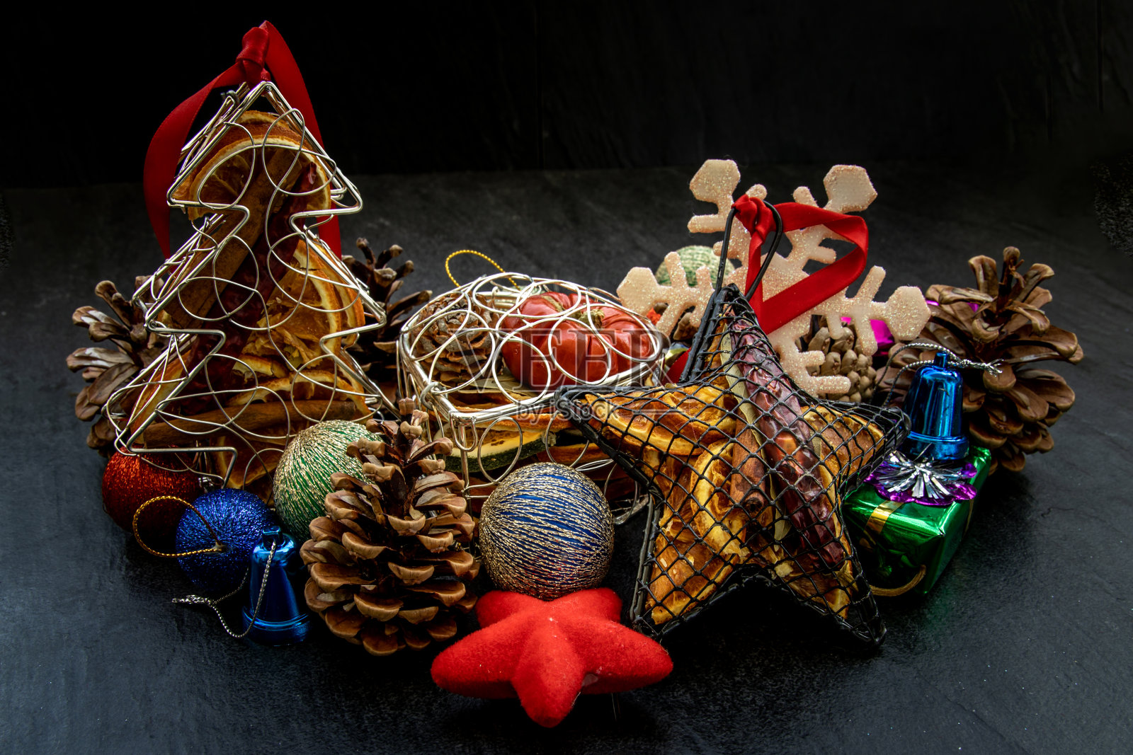 圣诞节装饰品：小树枝圣诞树、棕色天然松果和圣诞小鹿与各种水果在深色背景上照片摄影图片