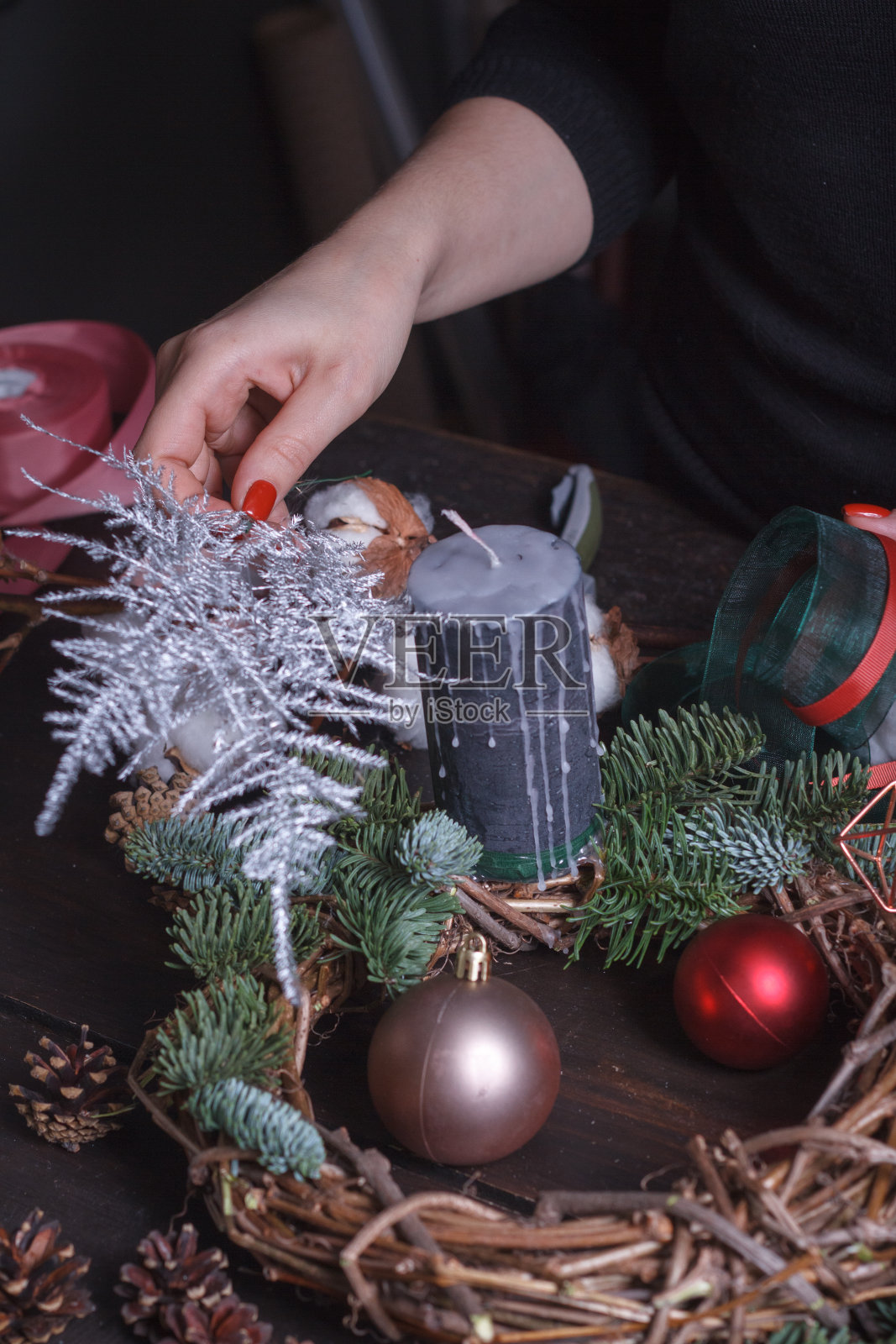 一个女性花商制作的冷杉树枝圣诞花环的特写，圣诞泡沫和自然装饰，选择性的焦点照片摄影图片
