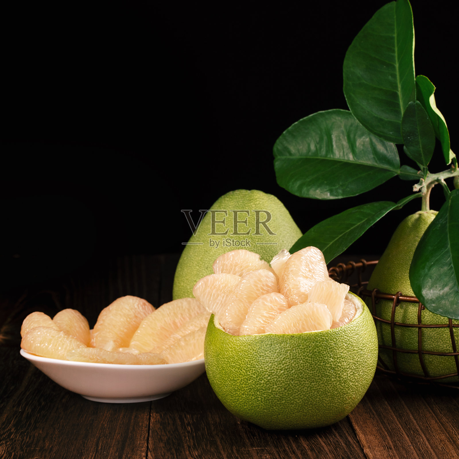 新鲜去皮柚子、葡萄柚、绿叶柚子放在深色木板桌上。临近中秋的季节水果，收起来，拷贝空间照片摄影图片