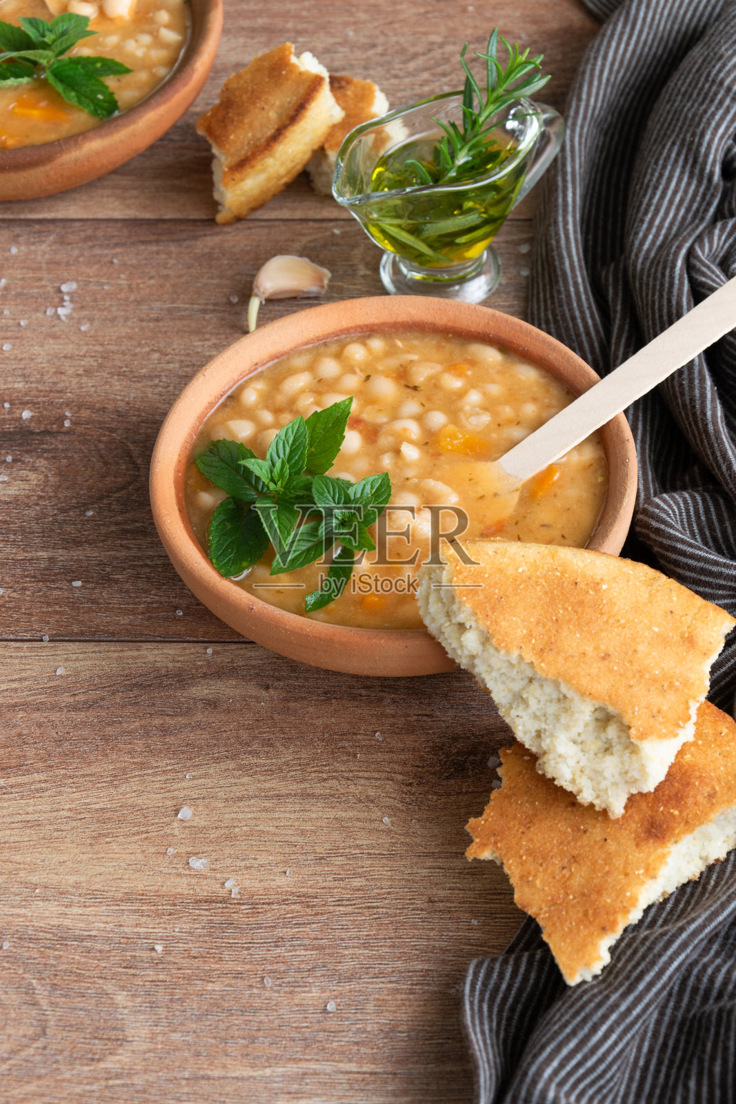 传统热豆汤配玉米面包、大蒜和橄榄油，健康素食菜肴照片摄影图片
