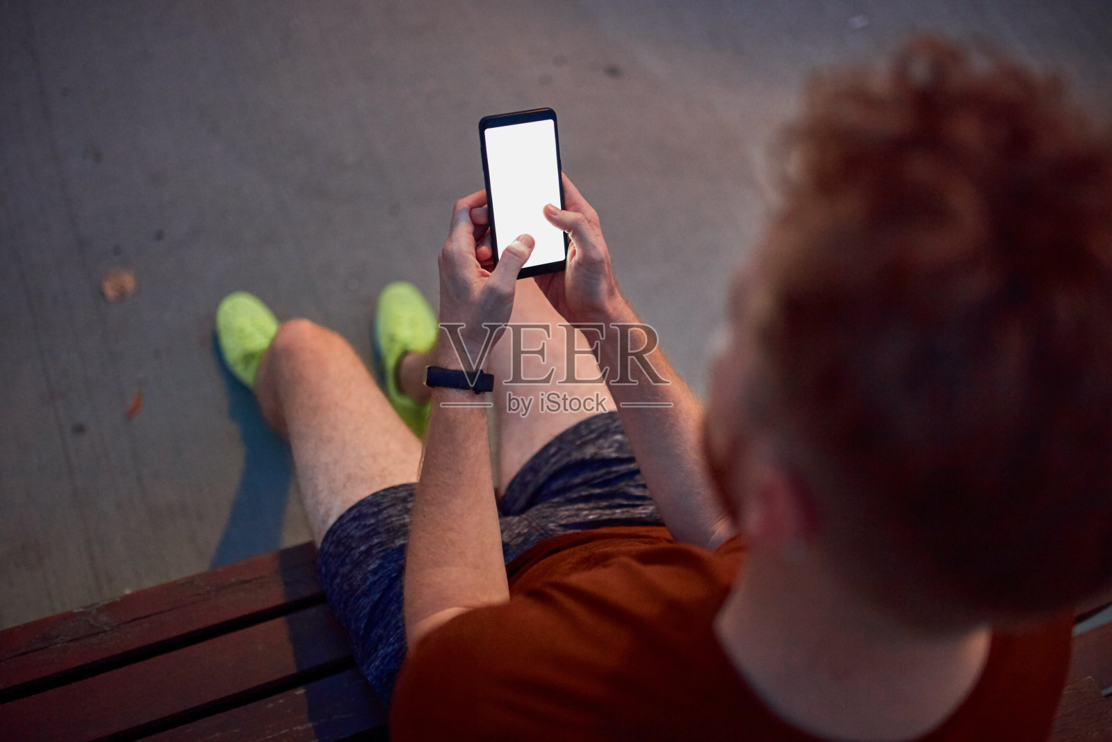 一名男子晚上在城市公园里用手机。照片摄影图片