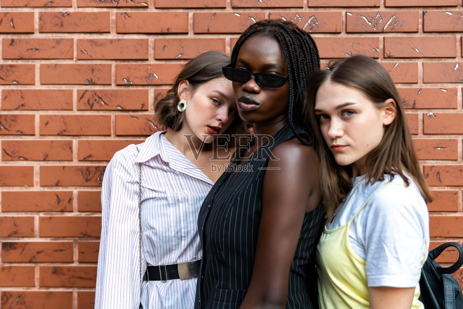 穿着休闲服装的多民族女孩在红砖墙上拍摄的半身像照片摄影图片
