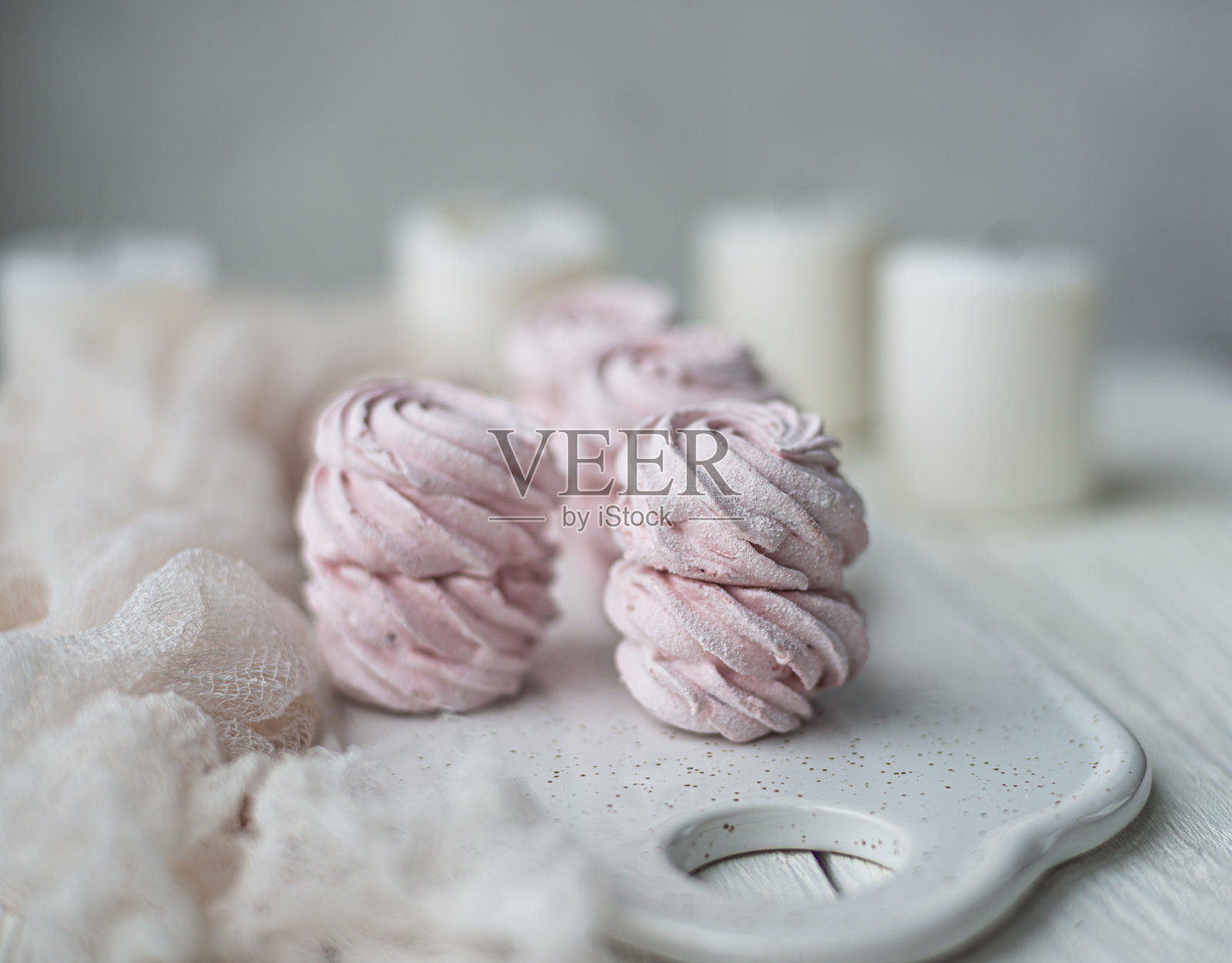 自制的棉花糖和风和蜡烛在白色的盘子上轻木桌子。粉色甜美的自制棉花糖或棉花糖。白色背景上五颜六色的蛋白糖霜。甜点照片摄影图片