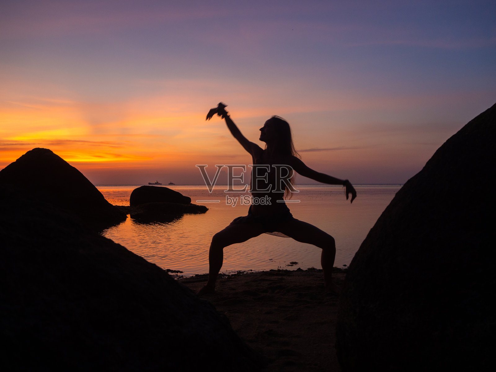 多彩日落背景下在海滩上跳舞的女人剪影照片摄影图片