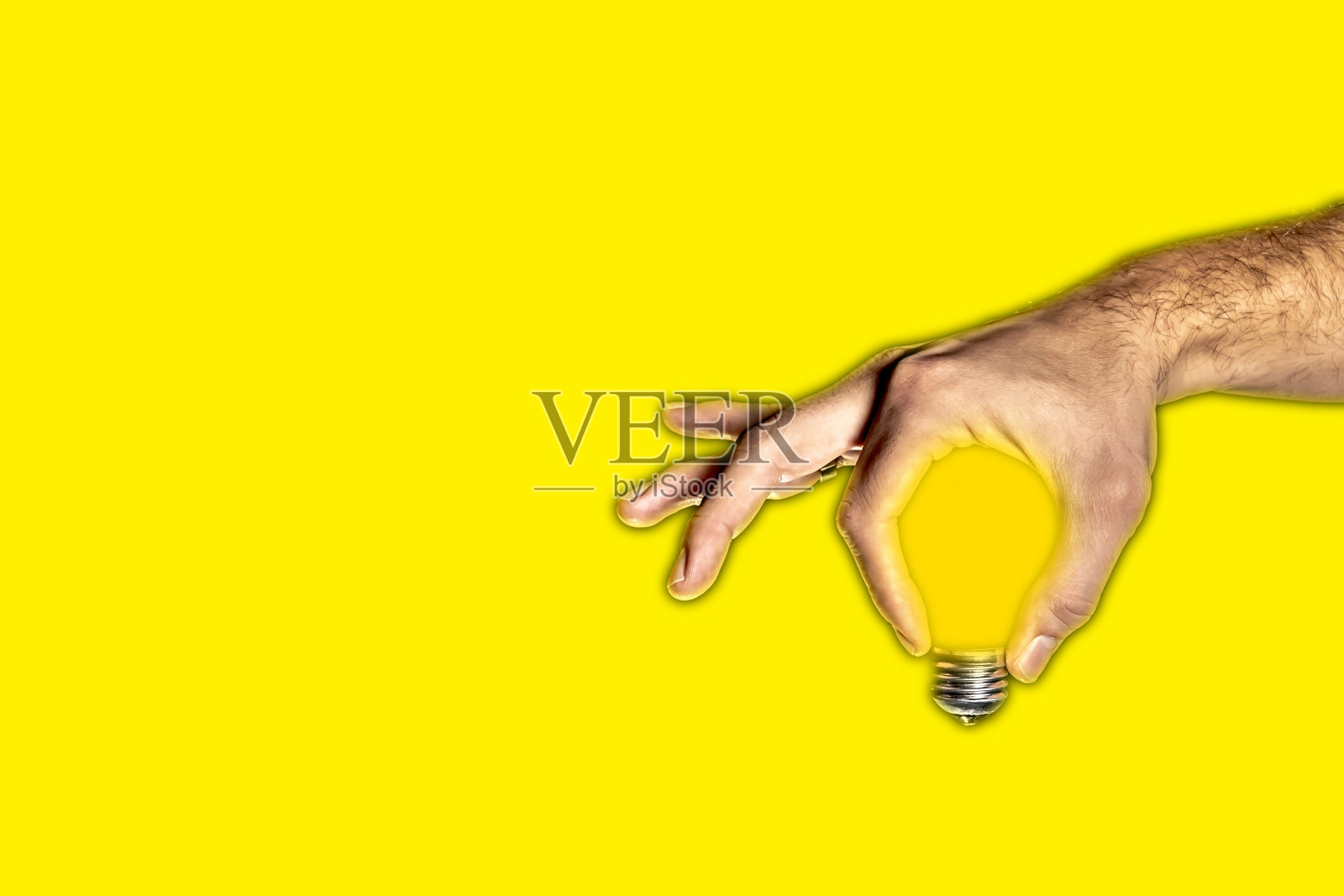 人手中的灯泡，黄色背景照片摄影图片