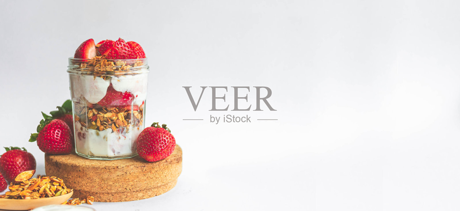 用健康的格兰诺拉麦片、草莓和希腊酸奶做成的美味冻糕。横幅的创意，角度拍摄。照片摄影图片