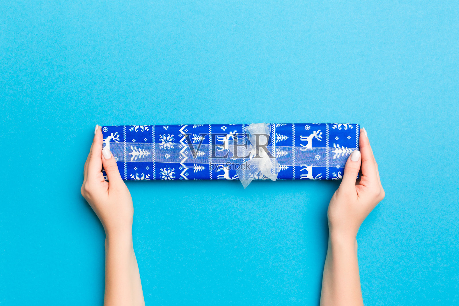 女人手臂抱着礼品盒与彩色丝带在蓝色的桌子背景，俯视图和复制空间为您设计照片摄影图片