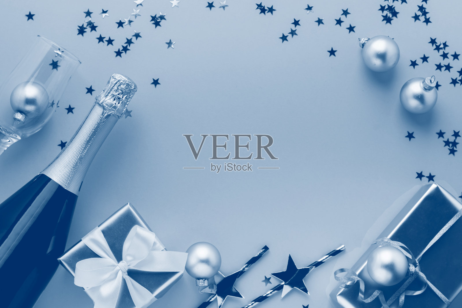 闪亮的纸吸管瓶香槟酒礼品与缎子蝴蝶结在蓝色的背景。复制空间放置文本设计。照片摄影图片