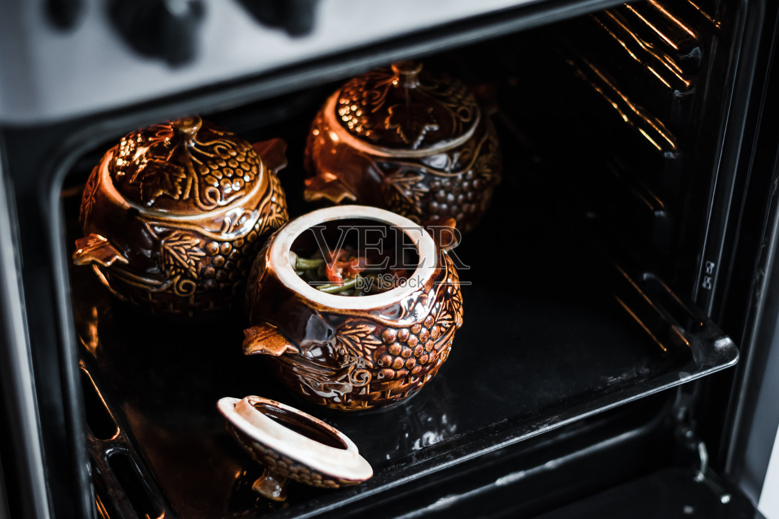 菜豆配肉，土豆，番茄，蘑菇，奶酪和香草，蛋黄酱，在棕色锅煮照片摄影图片