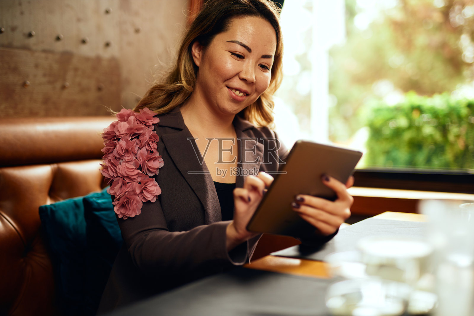 美丽的亚洲女人喝着咖啡，看着她的平板电脑照片摄影图片