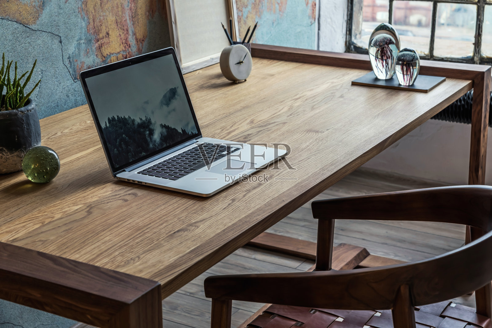 时尚的loft公寓办公空间室内设计，木制书桌、椅子、办公用品、笔记本电脑、植物和优雅的配饰。现代家庭办公室装饰。复古的墙。模板。照片摄影图片