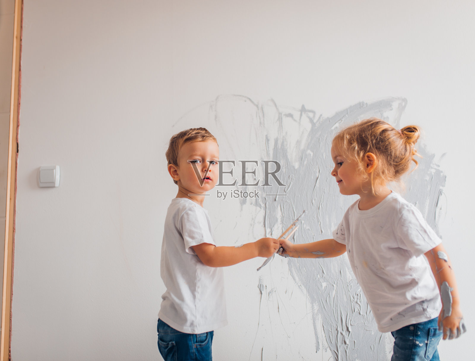 双胞胎兄弟在他们的房间里刷墙照片摄影图片