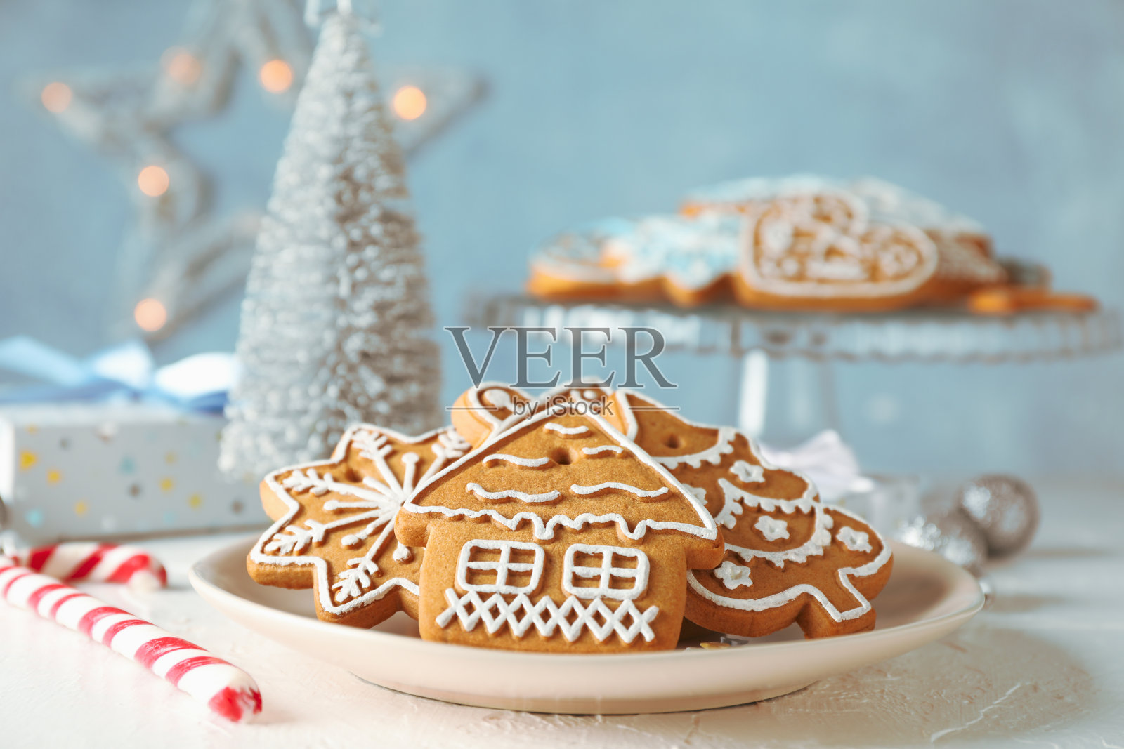 盘子上有圣诞饼干，圣诞树，玩具，礼品盒在白色的桌子上，在蓝色的背景，特写照片摄影图片