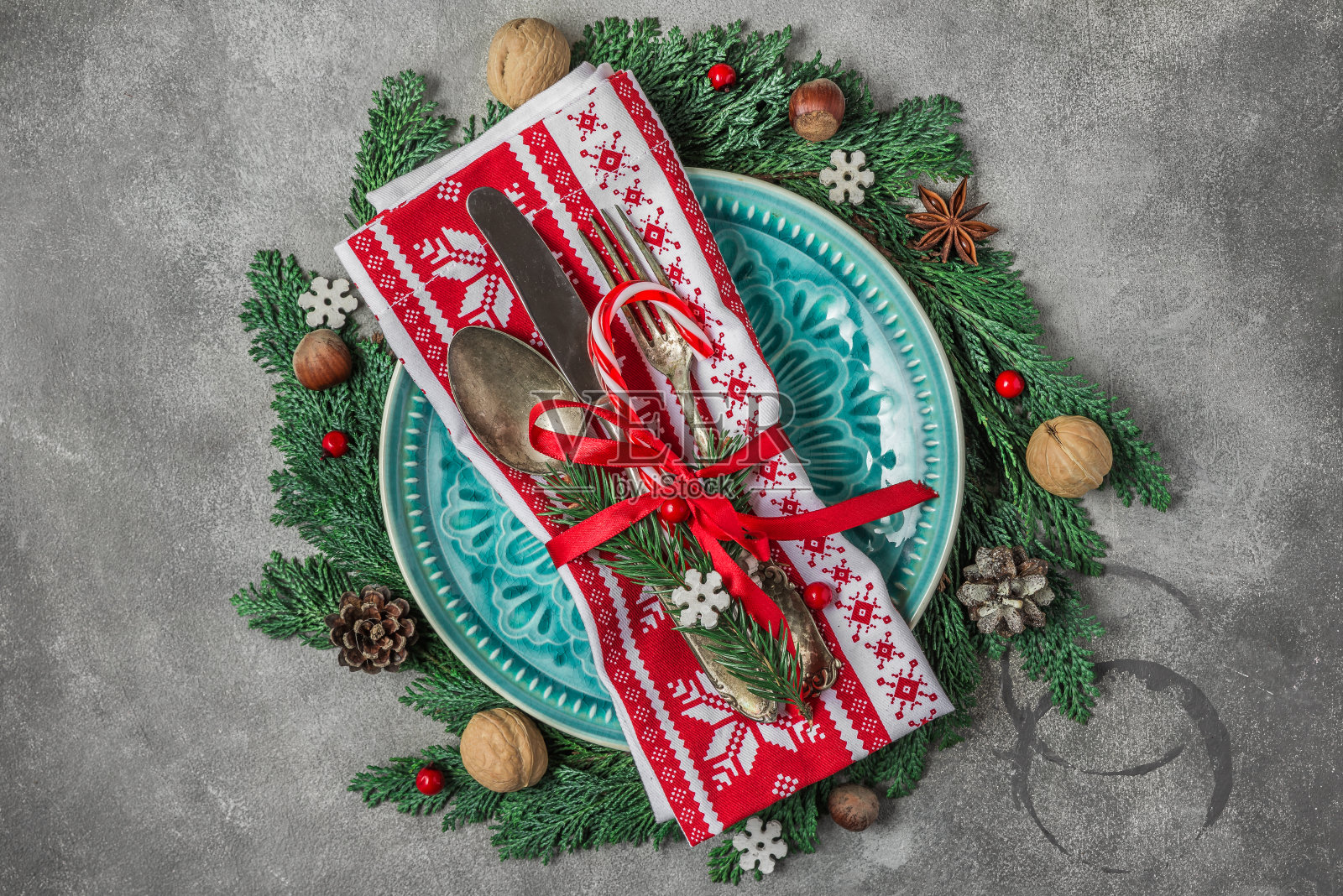 圣诞餐桌上摆放着盘子，餐具，节日装饰品，冷杉树枝，坚果和浆果。俯视图照片摄影图片