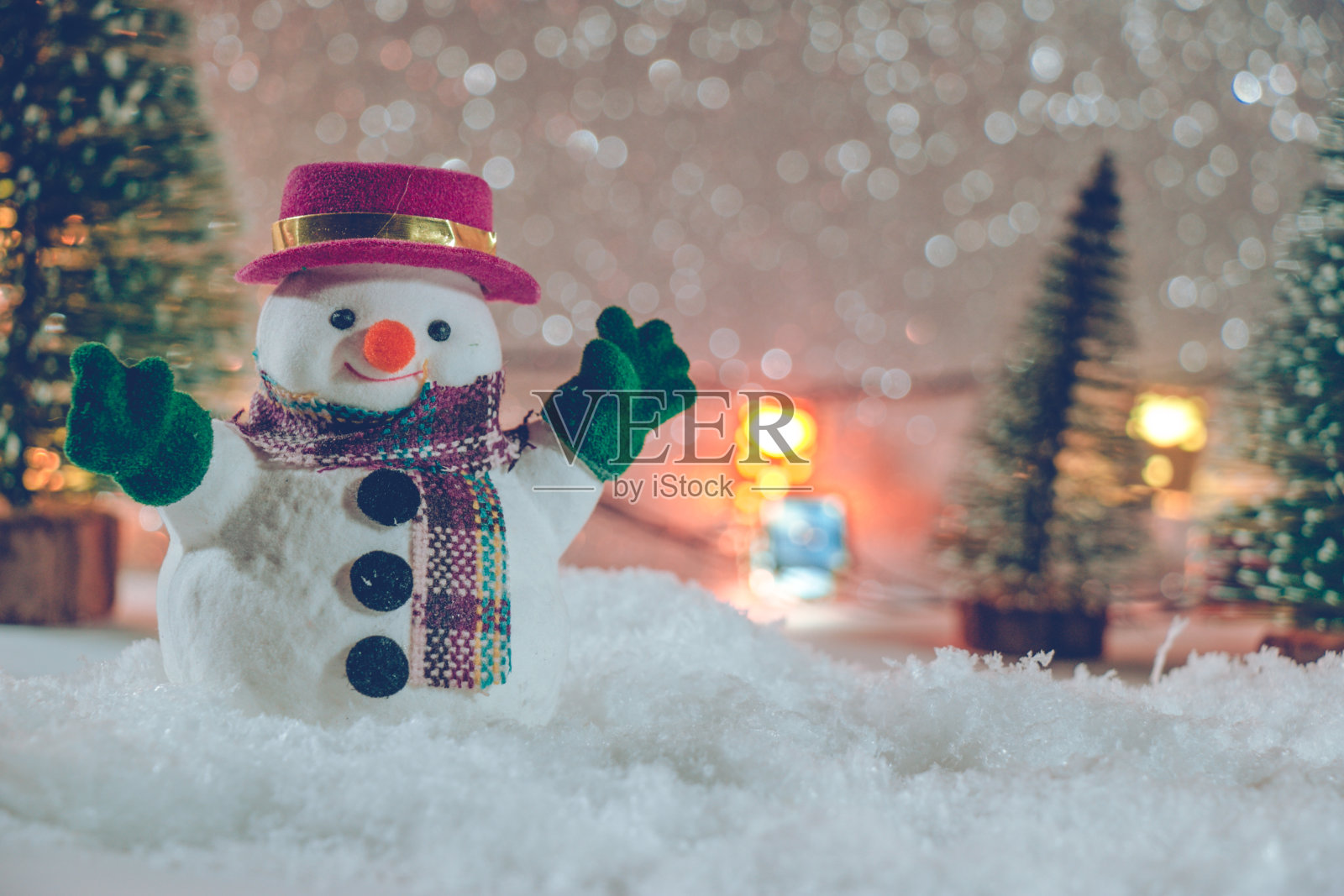 雪人站在雪堆里，在寂静的夜晚用圣诞树点缀，点亮了闪闪发光的背景。圣诞快乐，恭贺新禧。照片摄影图片