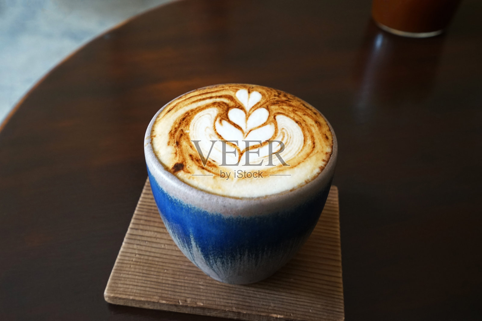 靠近陶瓷杯的热拿铁咖啡艺术在木制托盘桌上照片摄影图片
