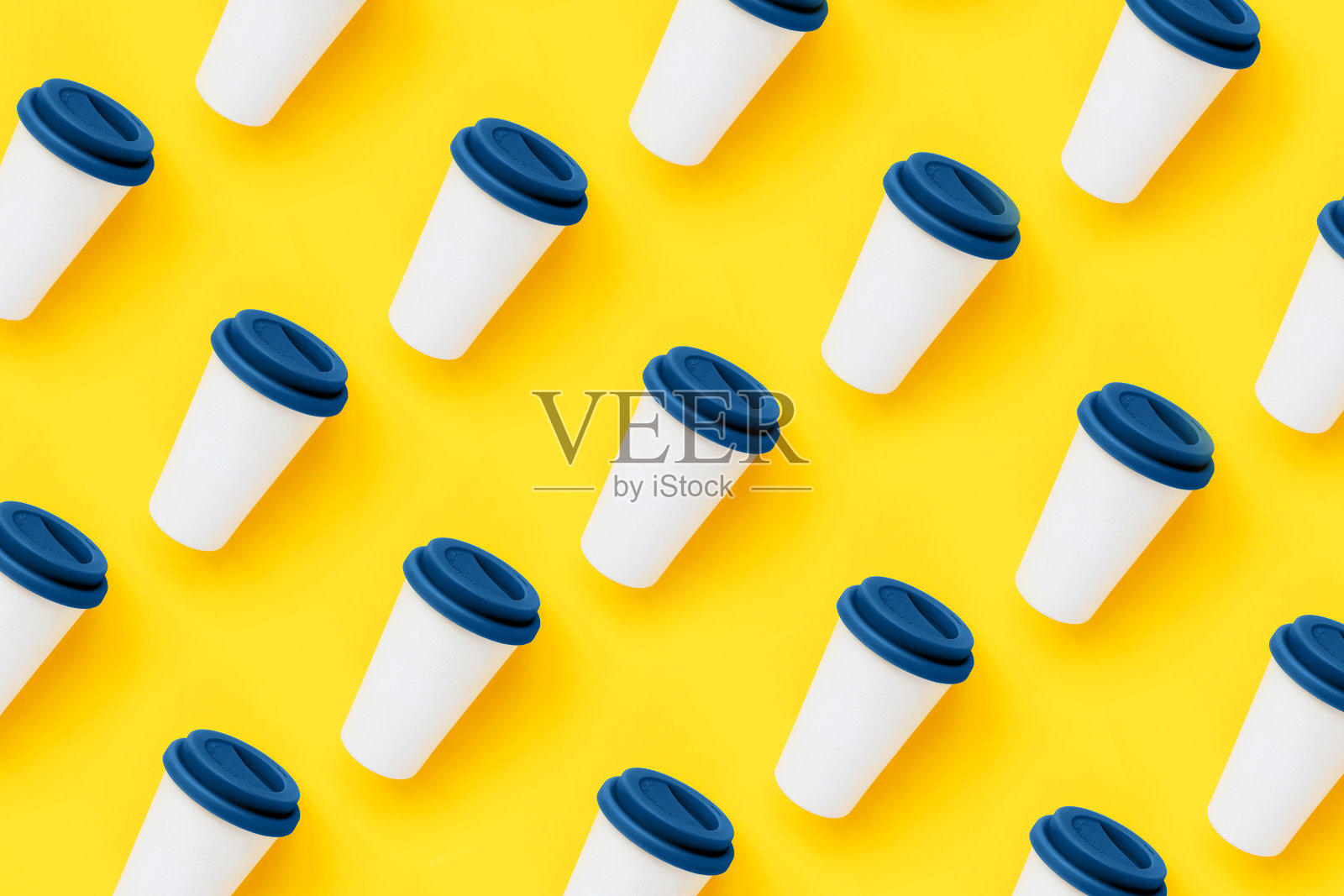 黄色背景上的白色竹制外带咖啡杯，配蓝色硅胶盖照片摄影图片