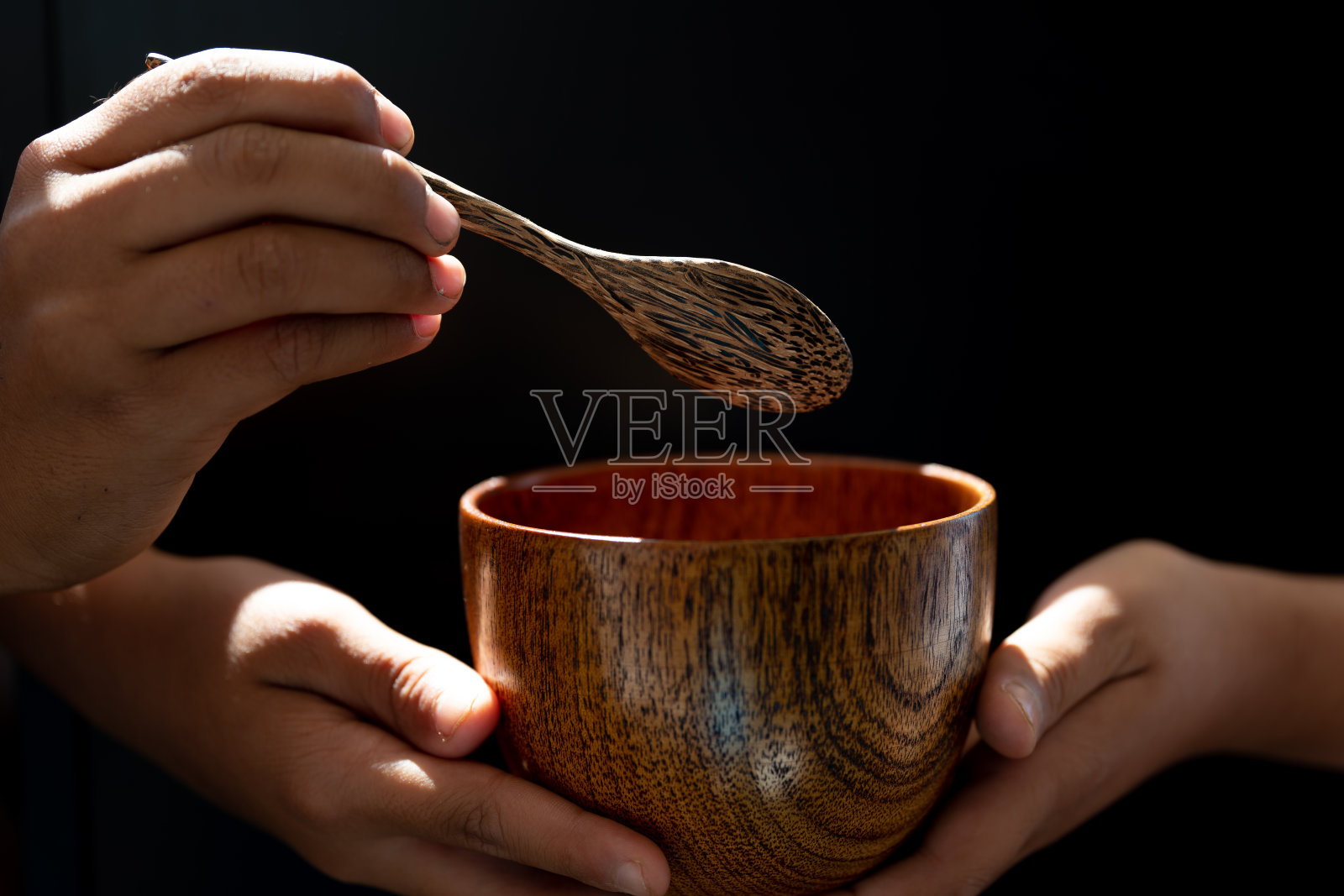 手握木汤孤立在黑色背景上，正面观照片摄影图片