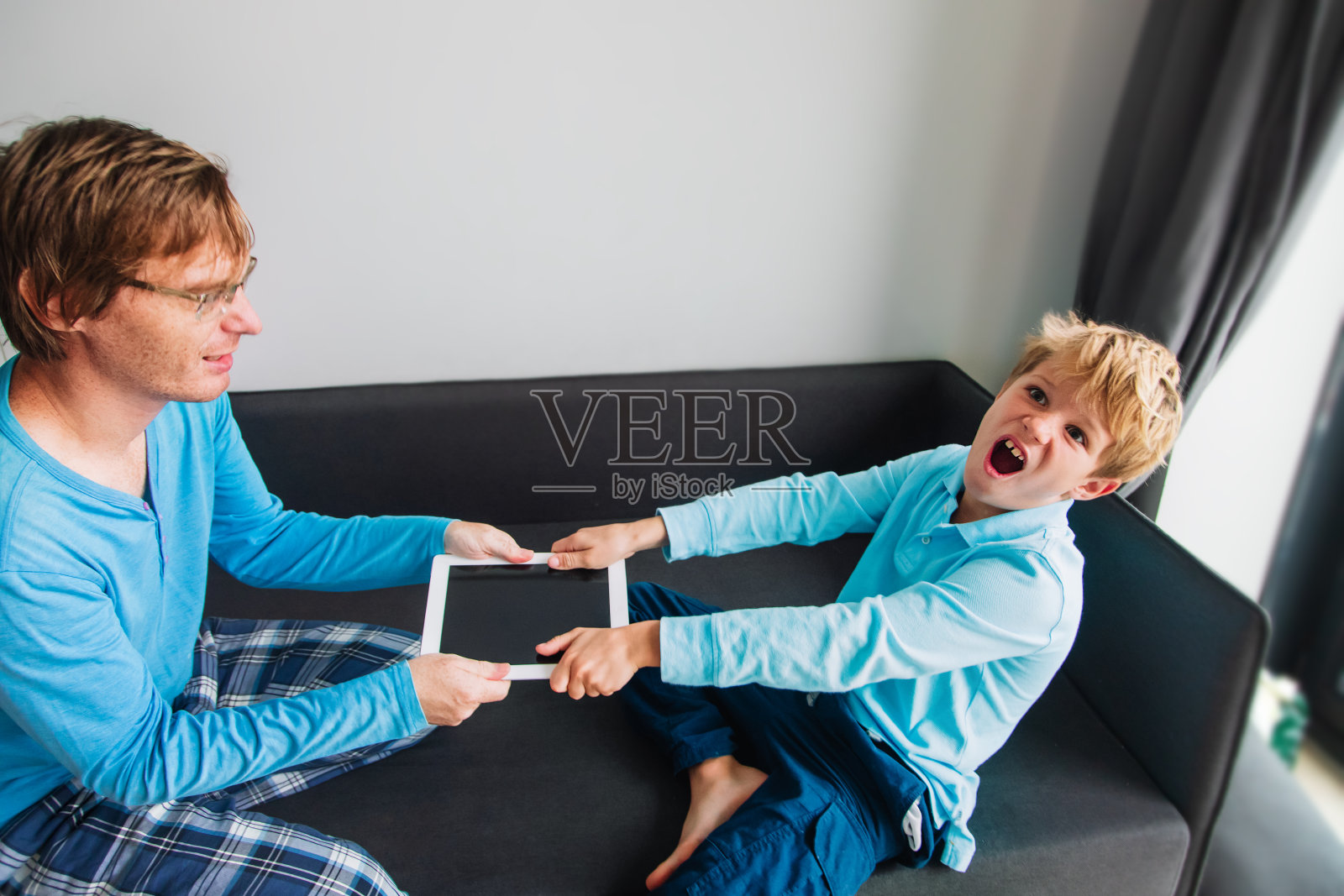 孩子沉迷电脑——父亲从愤怒的孩子手中拿走触摸板照片摄影图片