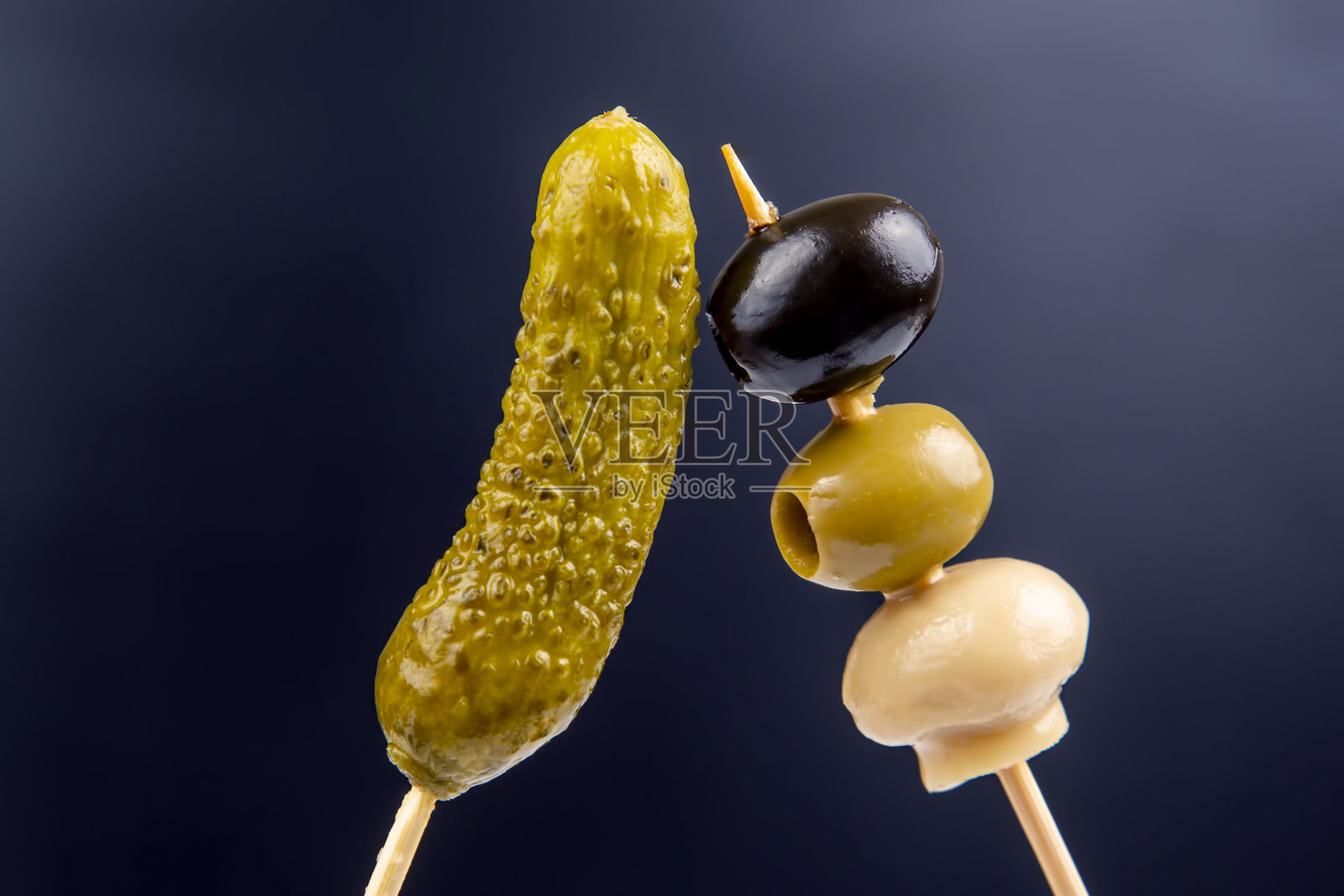 小雪早餐，罐头和腌黄瓜，橄榄和蘑菇在深蓝色的背景照片摄影图片