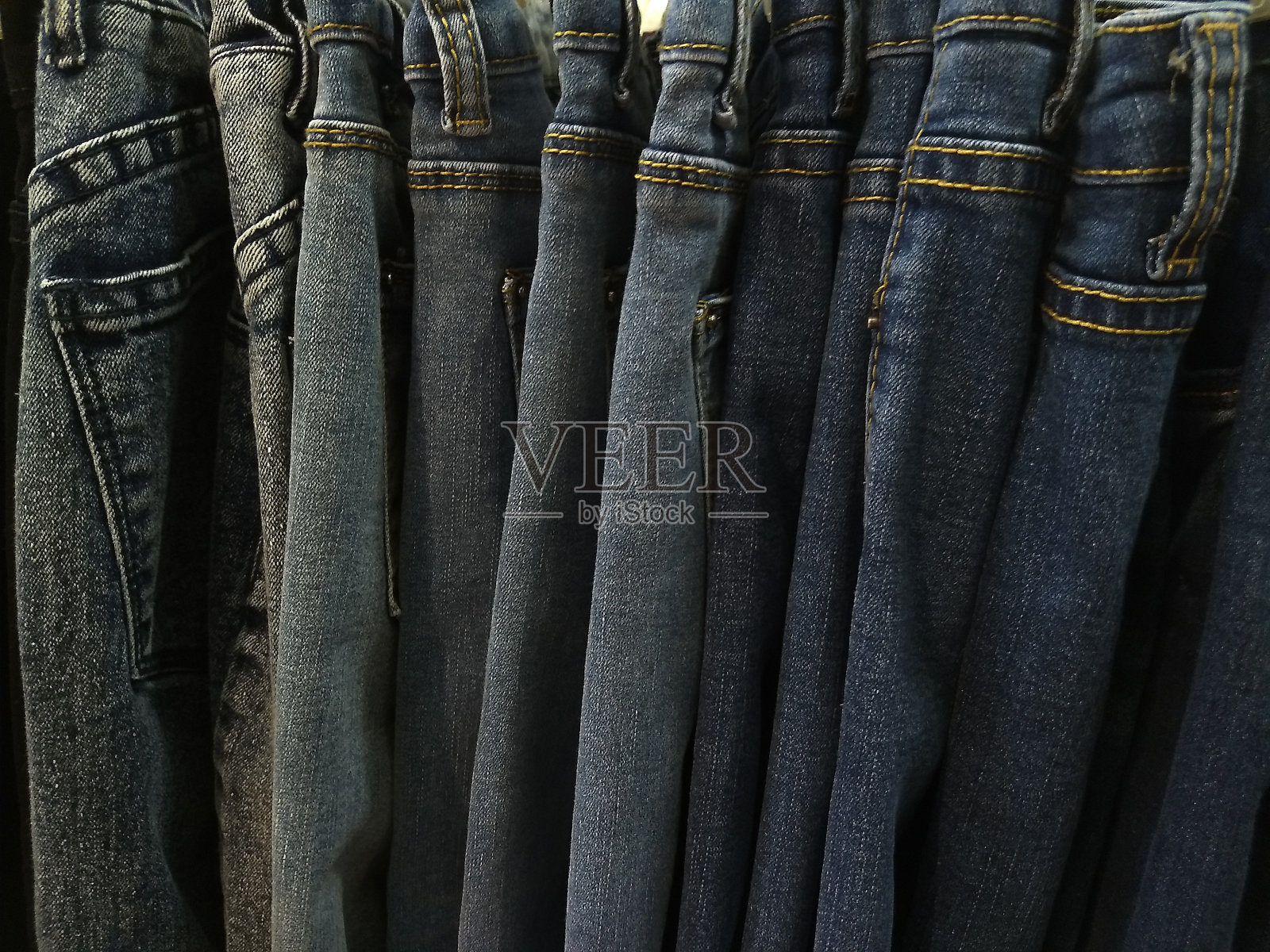 许多款式的牛仔裤，由不同的牛仔布，纹理，颜色挂在衣架上照片摄影图片