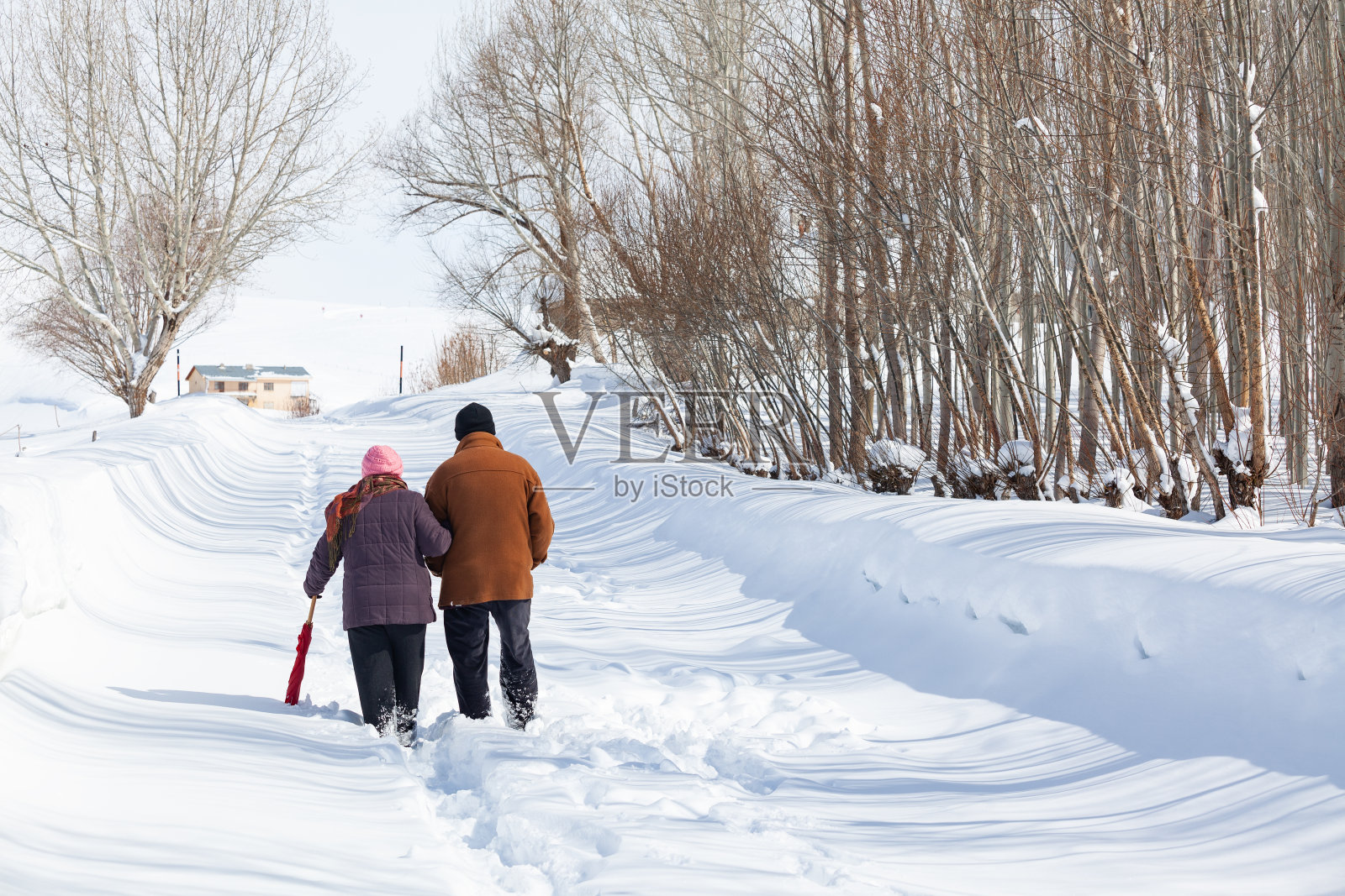 一对老年夫妇在下雪的乡村路上穿着暖和的衣服照片摄影图片