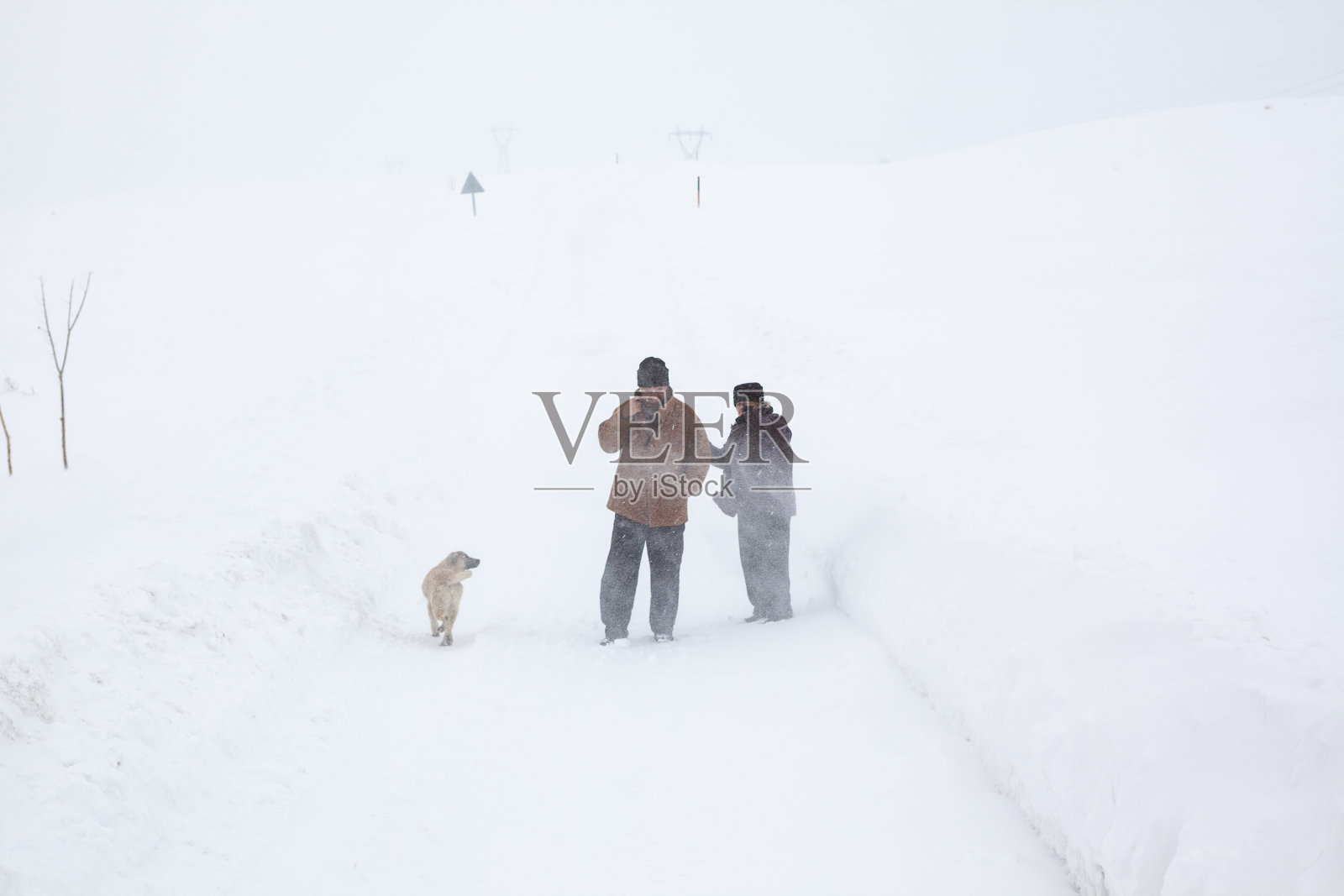 一对老年夫妇在下雪的乡村路上穿着暖和的衣服照片摄影图片