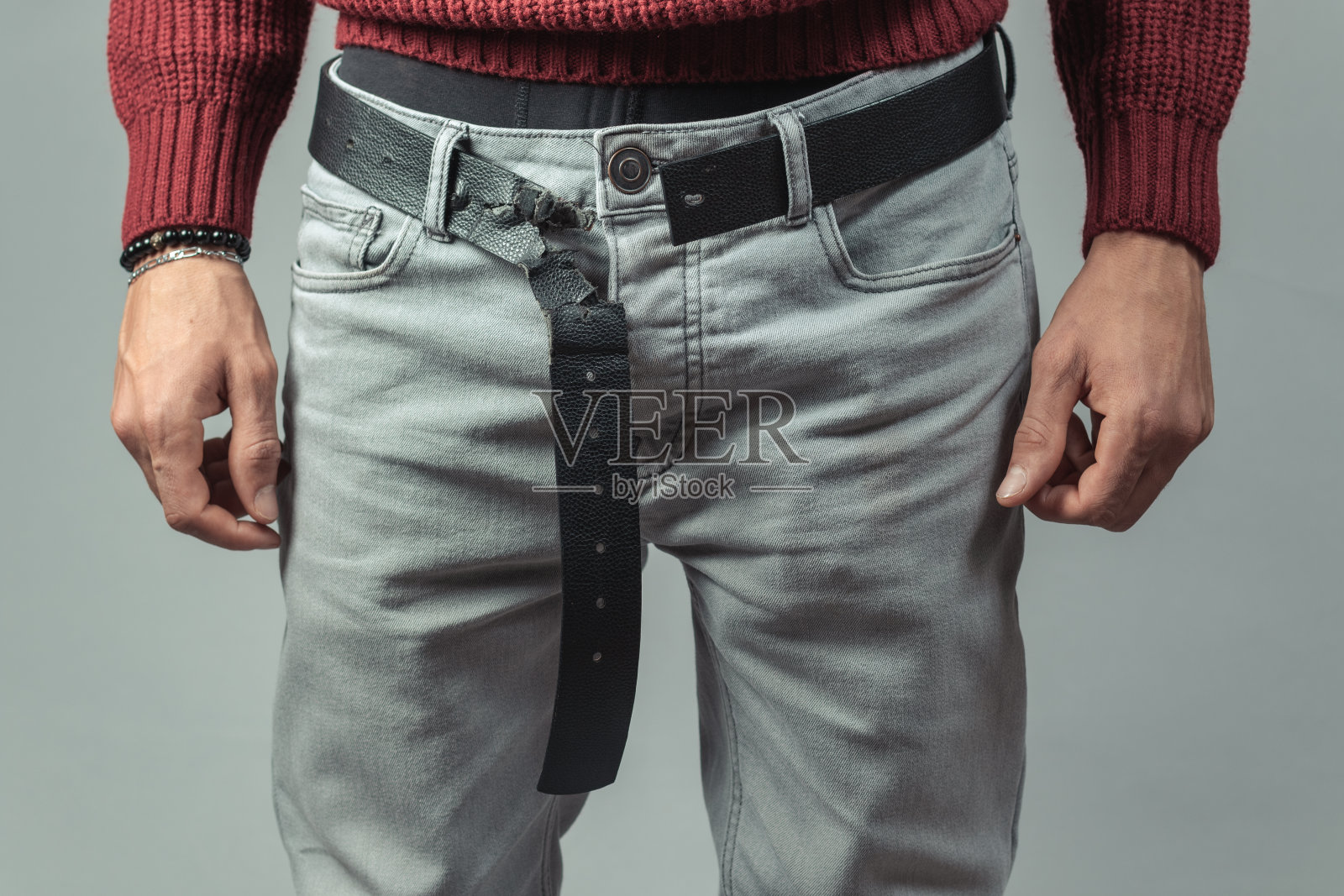 男人站着，腰间挂着损坏的皮带照片摄影图片