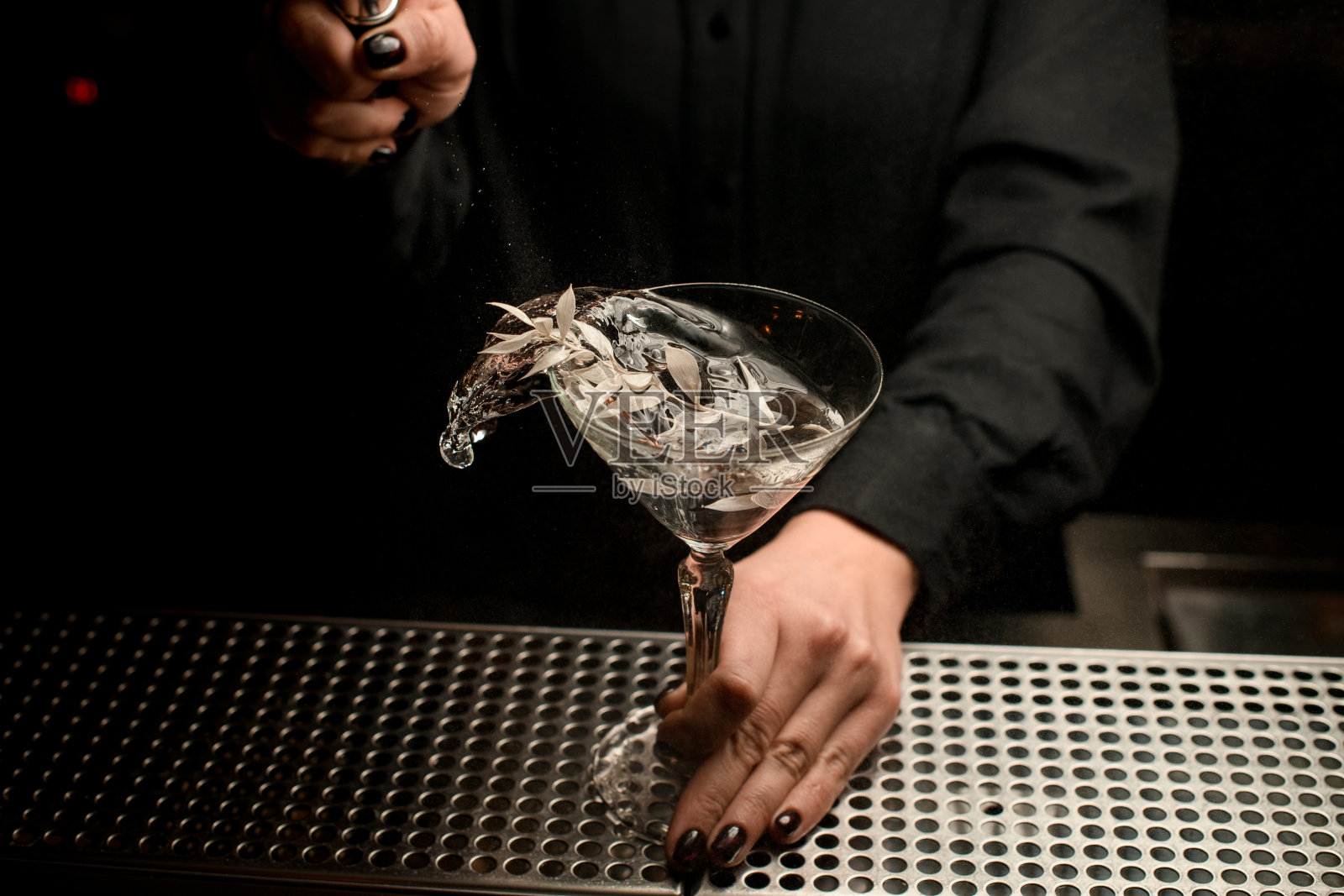 职业女调酒师服务透明的鸡尾酒在玻璃装饰着银色的树枝溅它照片摄影图片