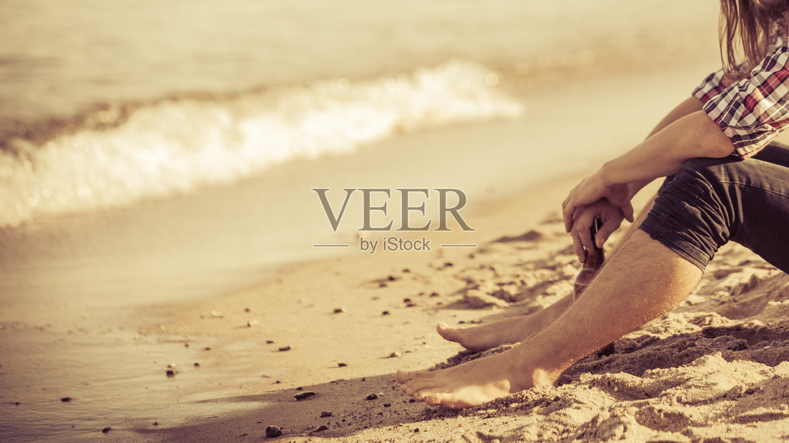 在海滩户外，手持酒瓶的沮丧男人照片摄影图片