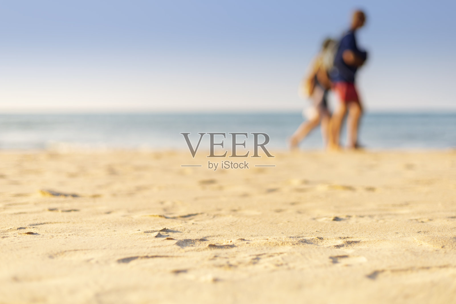 节日的概念。清晰的沙子和模糊的家伙，大海和清晰的天空背景。软聚焦和选择性聚焦砂。照片摄影图片