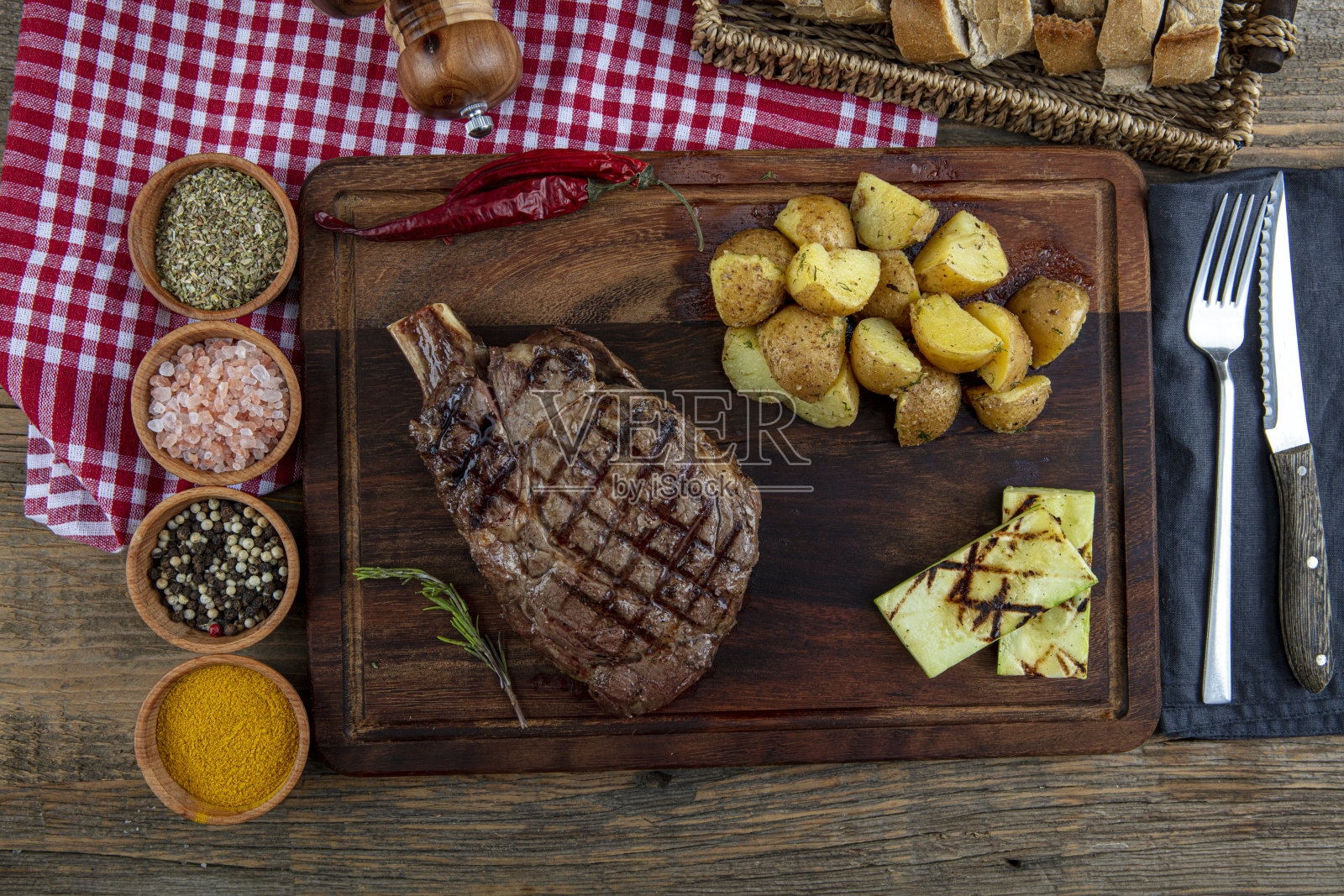 烤牛排配西红柿，大蒜和意大利辣酱放在切肉板上。照片摄影图片