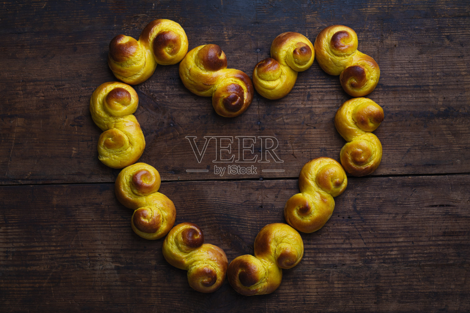 瑞典传统的圣诞面包放在质朴的木桌上，呈心形。照片摄影图片