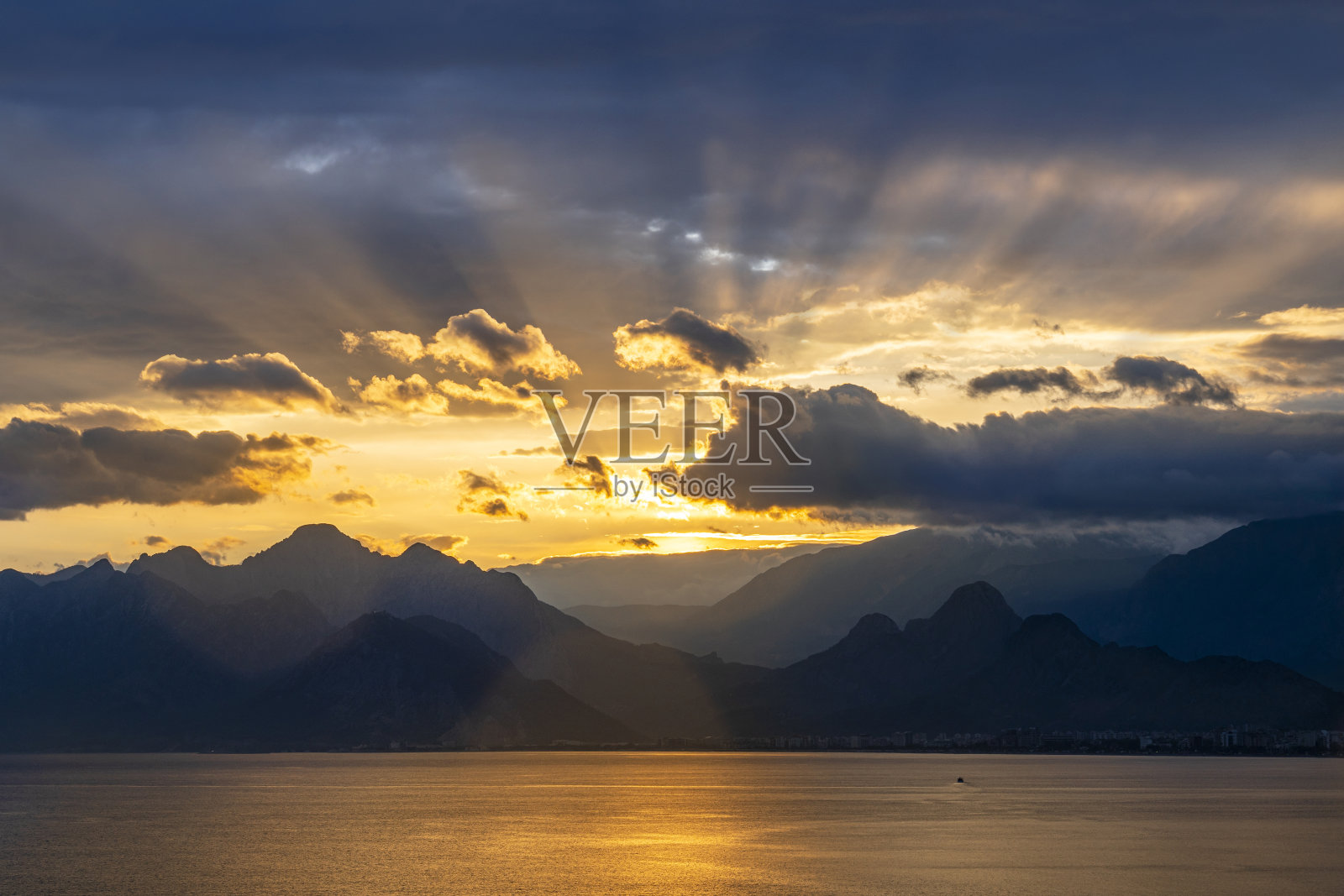 日落在安塔利亚著名的老城Konyaaltı海滩和海湾山。照片摄影图片
